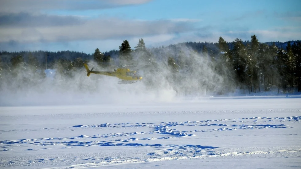 Helikoptern piskar upp snö som isolerar svagisen i Labbassjöns utlopp. Åtgärden ska göra att isen fryser fortare och håller för de älgar som ska passera på sin vandring. Foto: Jeanette Lindgren