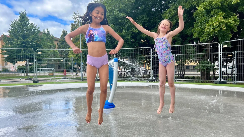Vännerna, Amanda Isgren och Fahrije Sherifi, hoppar glatt runt vattenspridarna. 