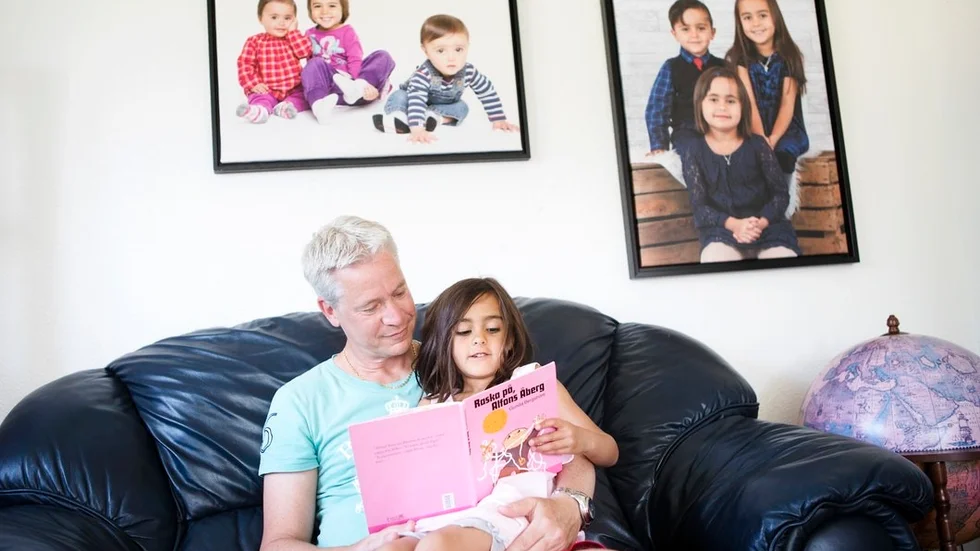 Alwina är i dag 6 år och tvillingarna Selma och Alexander 4 år. Här är det Alwina som läser saga med pappa Robert. "Vi lever som vilken svensk barnfamilj som helst", säger han.