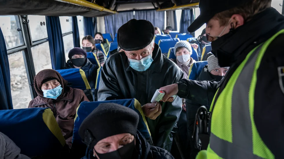 En polis mäter temperaturen på passagerare på bussen i närheten av i Ivano-Frankivsk i Ukraina. Arkivbild.