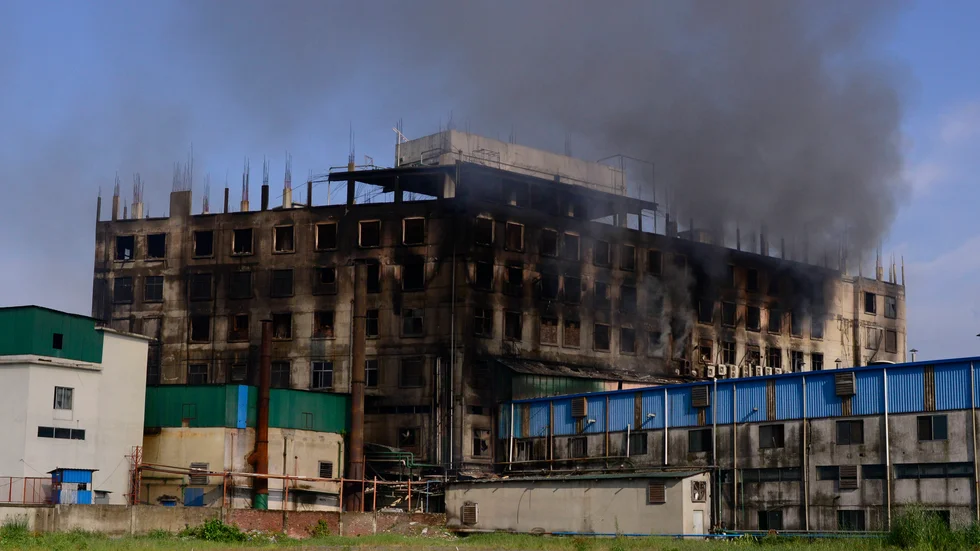 Rök stiger från den fabrik där en dödlig brand bröt ut utanför Dhaka, Bangladesh på fredagen.