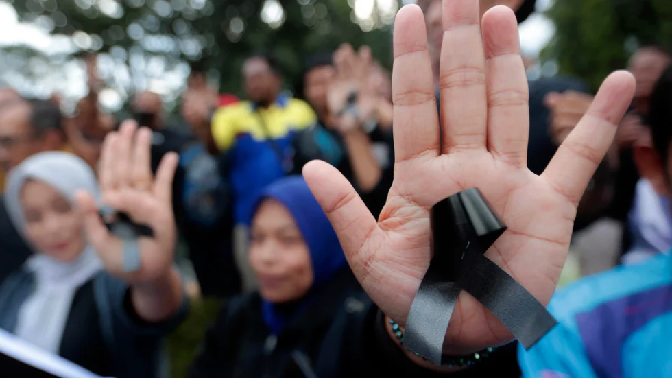 Kvinnor bär svarta rosetter som sorgesymbol för de 125 människor som förolyckades i samband med läktartragedin i Indonesien.