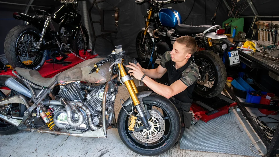 Sander Lunde kontrollerar strålkastaren på ett av sina motorcykelbyggen. 