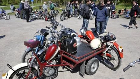 En "flaka" flakmoped av obestämd årgång ger stöd för två trötta medresenärer, mopedrallydeltagarna hade stannat för fika och vila i Gunnebo.