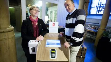 Eva Bergman, informatör i Nederluleå församling, och distriktsprästen Richard Marklund visar hur kollektomaten fungerar. Kollektomaten gör att kyrkobesökaren kan skänka kollekt med ett vanligt bankkort. Kvittot lägger man sedan i kollekthåven om man vill. Foto: PÄR BÄCKSTRÖM