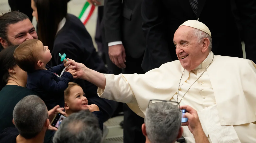 En skojfrisk påve Franciskus tar nappen från ett barn i samband med påvens veckoliga tal i Vatikanen.