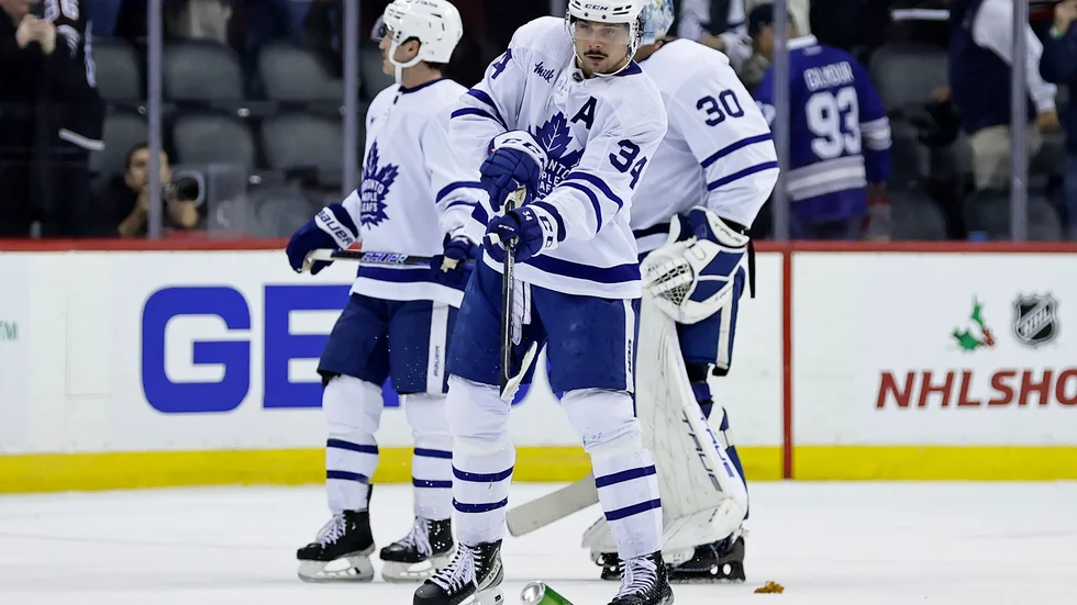 Torontos center Auston Matthews skjuter undan en burk efter att ilskna New Jersey-fans fyllt isen med allehanda skräp under nattens NHL-match.