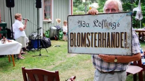 Östhammar 28 juli 2013. Karl- Fredrik Ingmarsson, ordförande i Frösåkers hembygdsförening, håller upp en affärsskylt från föreningens skyltsamling.