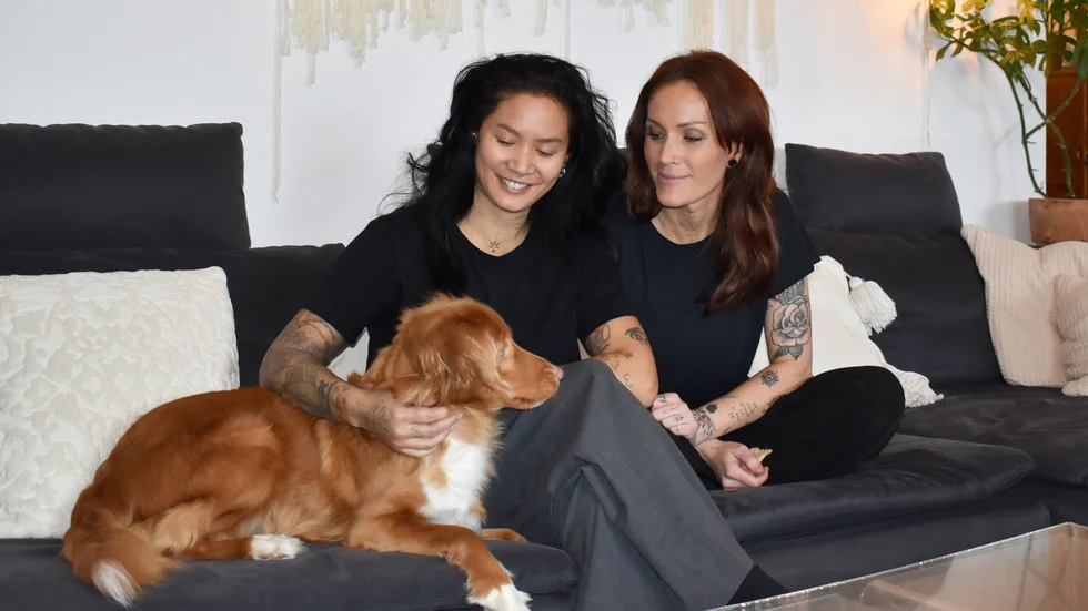 Elin Karlsson och Sandra Johansson sitter med hunden Zita i hemmets enda Ikea-möbel, nämligen soffan.