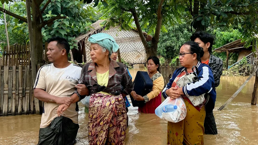 Invånare i en liten by i Naypyidaw-regionen i Myanmar står med sina tillhörigheter i händerna efter de omfattande översvämningarna i landet. Bilden är tagen den 13 september.