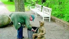 Dan Wolgers "Sittande pojke med korg". Turist rotar efter souvenirer i askan efter elden i pojkens korg.