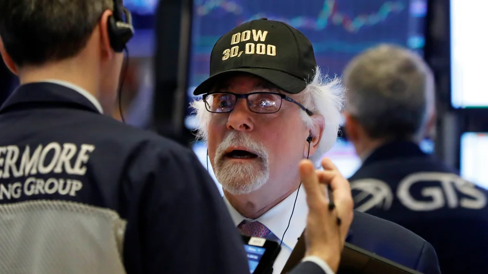 En aktiehandlare på Wall Street med en keps med texten "Dow 30|000". Dow Jones industriindex har under handelsdagen nått en ny milstolpe.