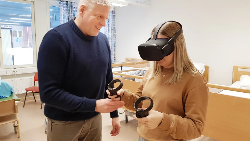 Hemsjukvårdens rehabchef Jörgen Divert visar vård- och omsorgseleven Elin Viklund hur man genom VR-glasögonen får undervisning i att förflytta brukare på rätt sätt.
