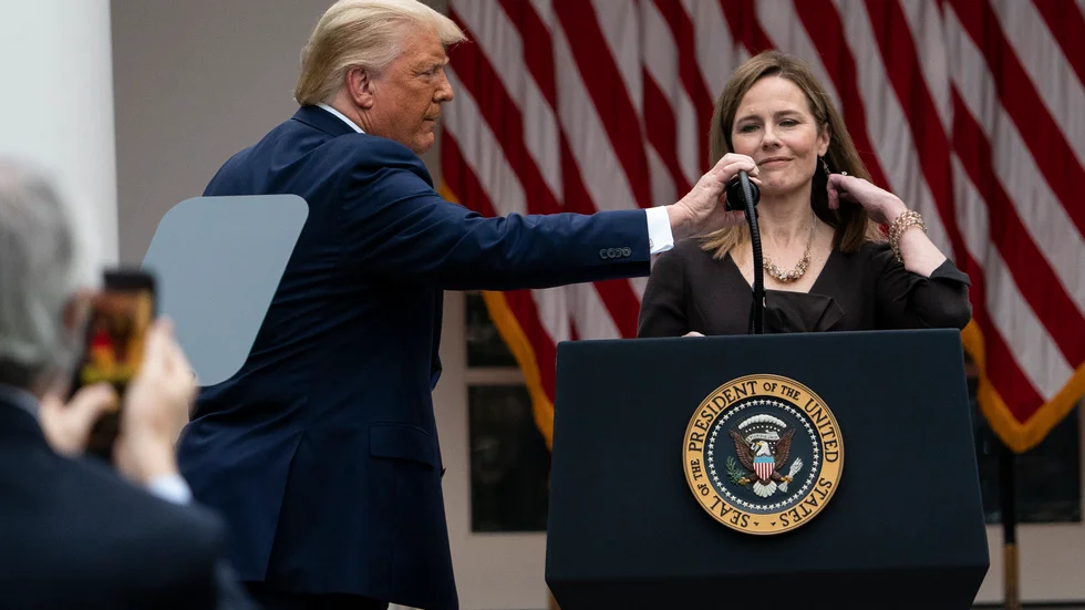 President Donald Trump justerar mikrofonen åt Amy Coney Barrett i Vita husets rosenträdgård.
