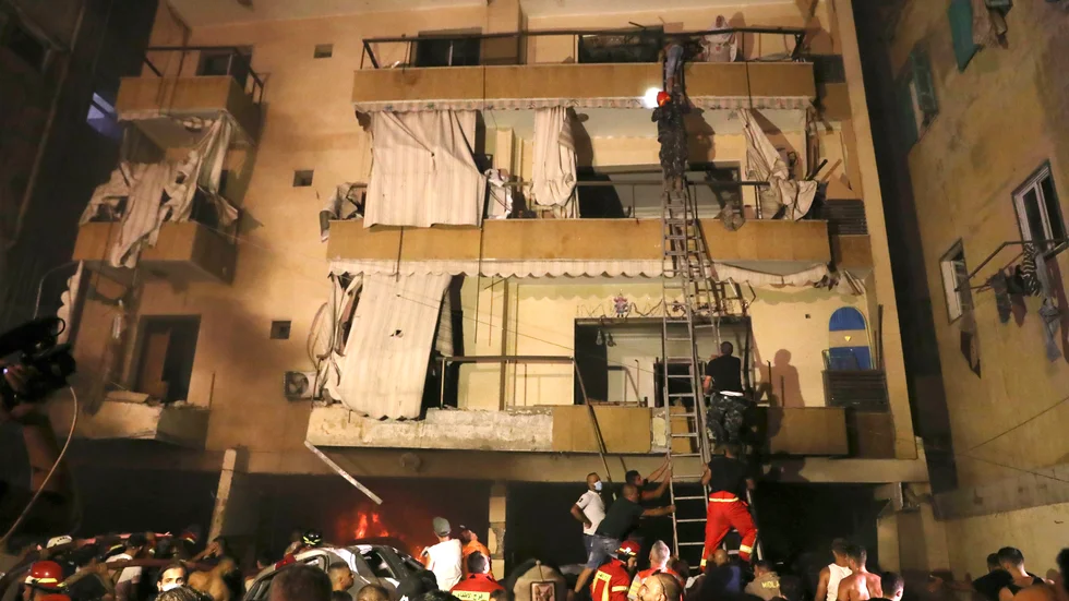 Människor får hjälp att ta sig ut ur sina hem sedan en bränsletank exploderat i Beirut på fredagen.