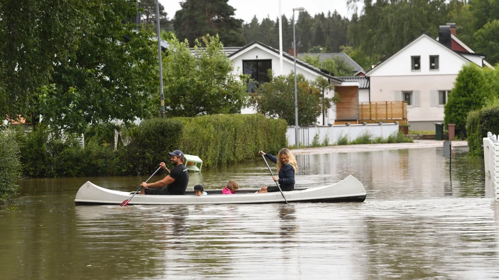 En familj i Gävle paddlar kanot genom ett översvämmat villaområde efter de kraftiga skyfallen. Bild från 18 augusti.