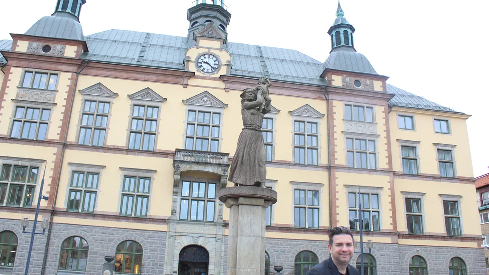 Jimmy Jansson är född 1978. Här står han på Fristadstorget i Eskilstuna framför fontänskulpturen "Arbetets ära och glädje" av Ivar Johnsson från 1942 och Stadshuset från 1897.