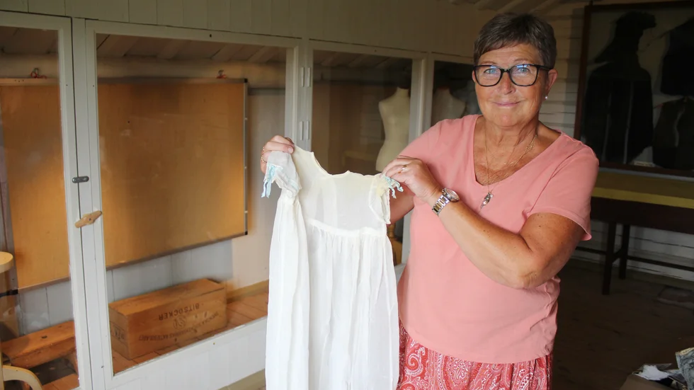 Monica Remning visar upp en av de dopklänningar från Finspångs lasarett, som ska vara med på nya utställningen hos hembygdsföreningen.