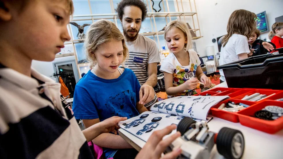 Påsklov. Syskonen Barch-Holst sätter legobitarna på plats med hjälp av instruktören Daniel.
