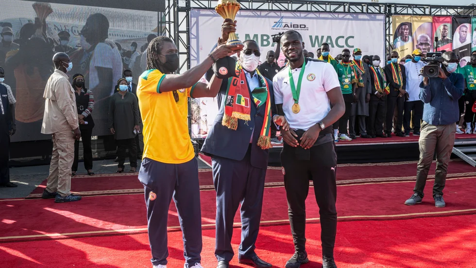 Förbundskapten Aliou Cissé, president Macky Sall och lagkaptenen Kalidou Koulibaly poserar med pokalen.