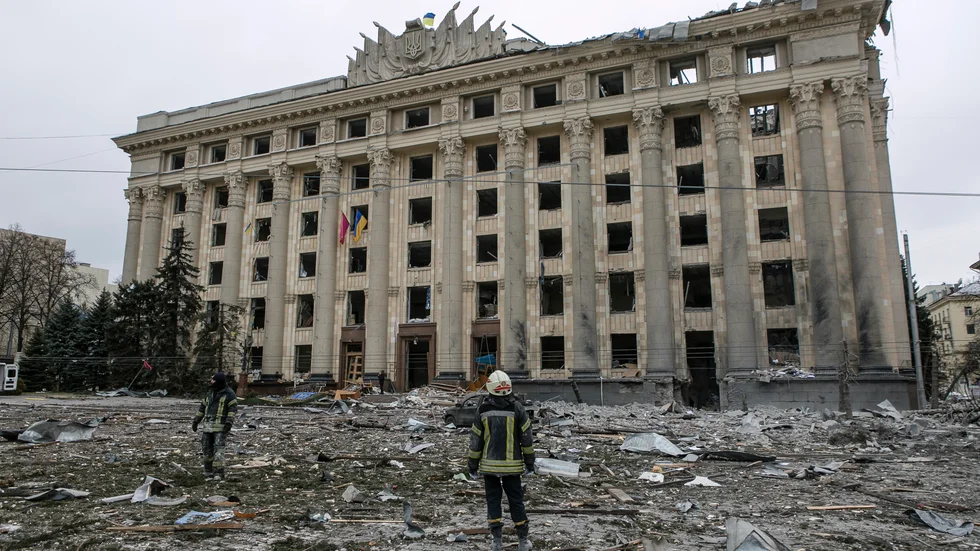 En medarbetare i den ukrainska räddningstjänsten står i förödelsen framför stadshuset i Charkiv, Ukrainas näst största stad.