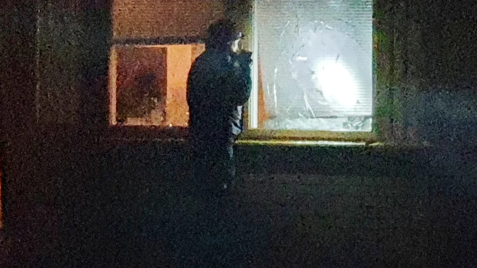 En polis undersöker de krossade fönstren till familjens bostad på torsdagskvällen.