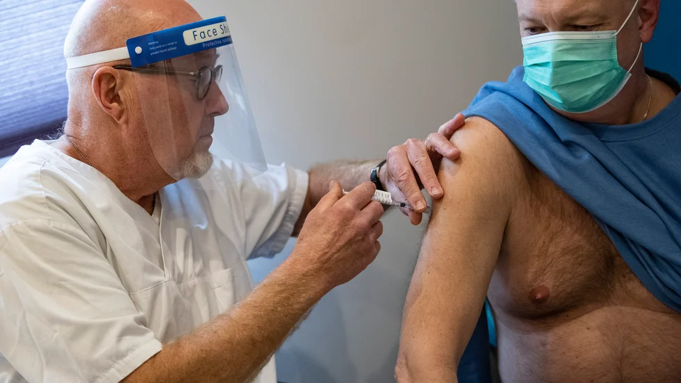 En spruta med coronavaccinet Comirnaty från Pfizer/Biontech sätts i högerarmen på en av dem som köat för vaccination i den nya vaccinationsbussen i Malmö.