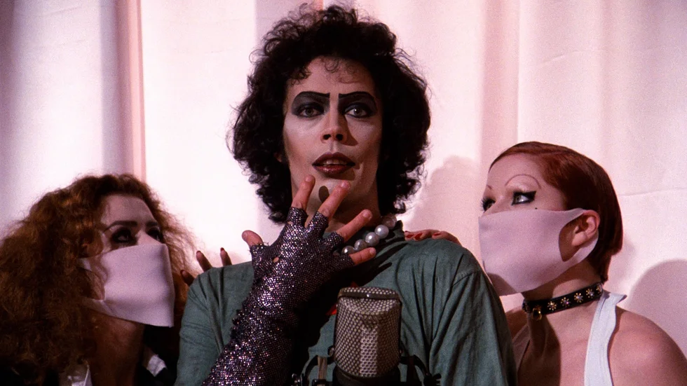 Den oefterhärmlige Tim Curry som Dr. Frank-N-Furter, flankerad av Magenta och Colombia spelade av Patricia Quinn och Little Nell.
