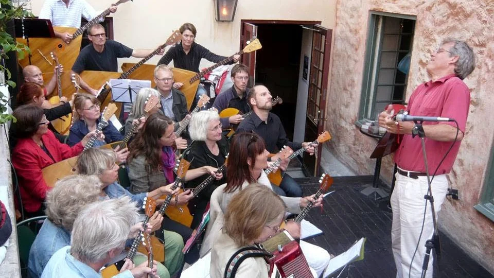 Gotlands Balalajkaorkester, som här gör ett bejublat framträdande utanför en av Visbys krogar, firar sina första 20 år som band med en konsert i St: Hansskolans aula på lördag eftermiddag.