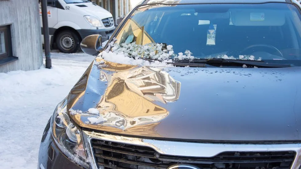 Buckla efter takras. Bilen är i riskzonen när snön släpper från taket.