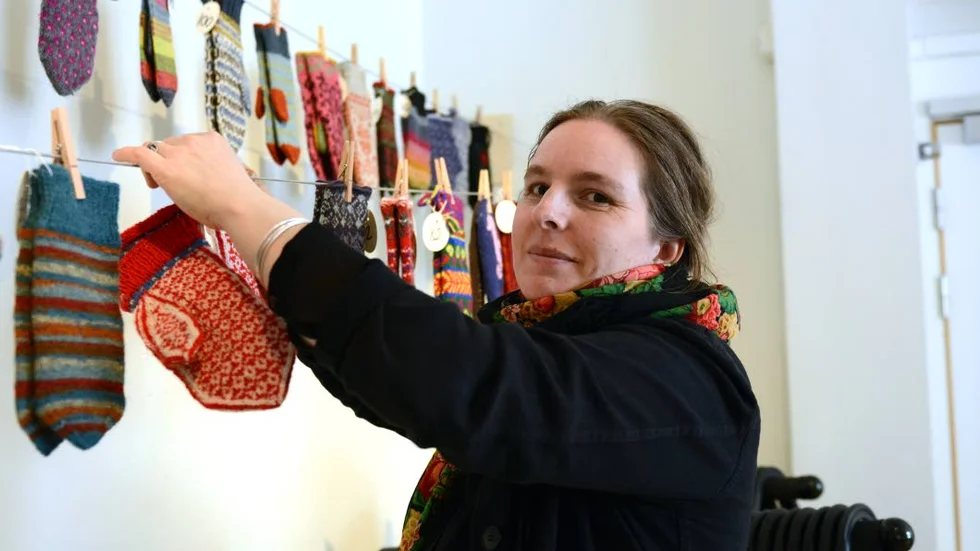 Vantar i långa rader. Karin Gradin, hemslöjdskonsulent hänger upp vantarna som folk från norr till söder skapat.