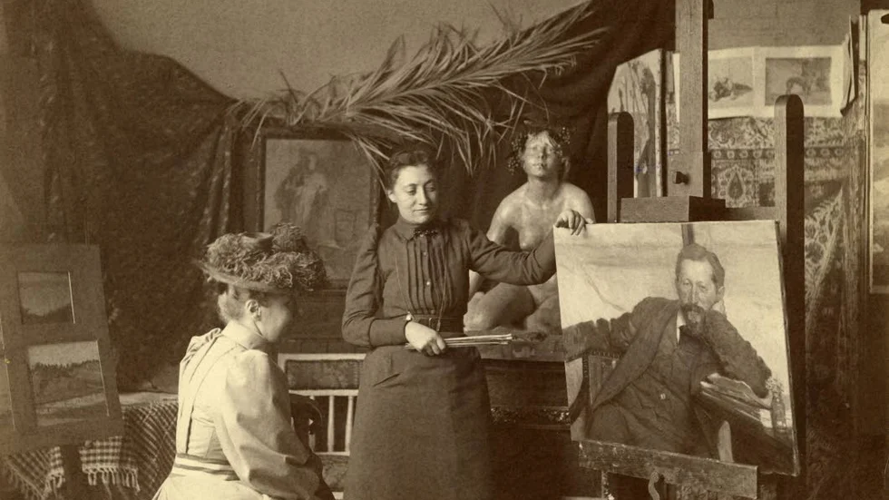 Eva Bonnier i sin ateljé med en okänd besökare och porträttet av Hjalmar Lundbohm på staffliet.