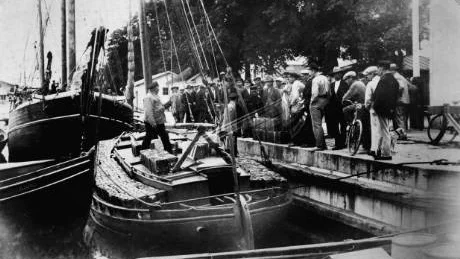 Det var många nyfikna som mötte tullarnas båt, nedlastad med smuggerlsprit, när hon lade till vid Skeppsbrons kaj i augusti 1930. Arkivbild: Kulbackens museum