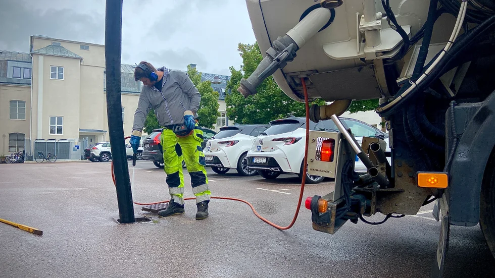 Spolbilschauffören Thomas Holtberget gör rent i en dagvattenbrunn som svämmat över.