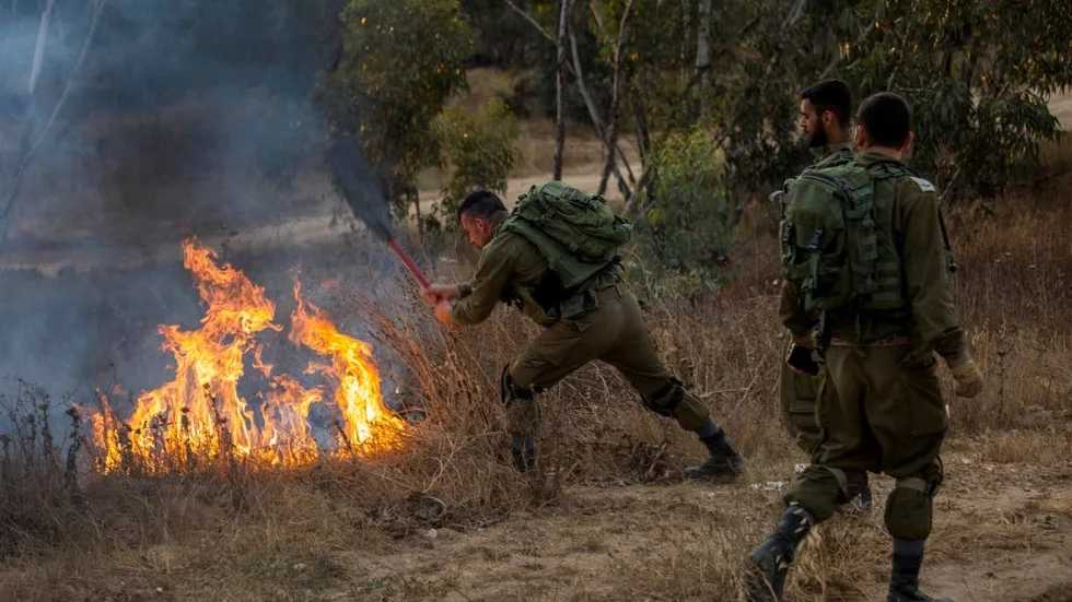 Israeliska soldater släcker eld som startats av brinnande flygande drackar som skickats mot civila mål av Hamas.