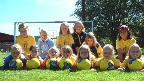 Tjejerna i 94-95-gruppen poserar glatt tillsammans med ledaren Mia Anspach inför en av många matcher på fotbollsskolan.