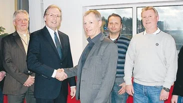 Komoris Europachef på försäljningssidan, Tony Carter, skakar hand med Peter Ihre från V-TAB sedan installationen av den moderna tryckpressen inletts.