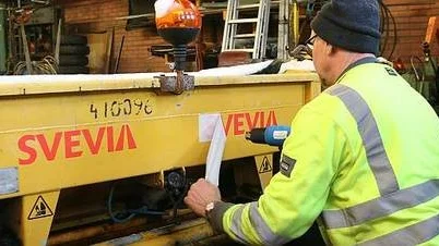 Per Rosén klistrar den nya logotypen på f d Vägverket produktions vagnspark i Tierp.