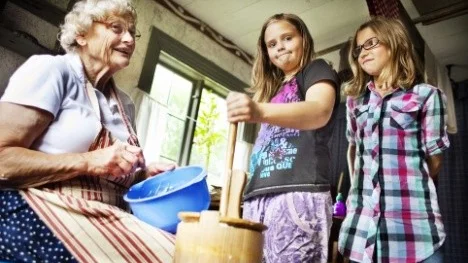 Berit Levén visar tvillingarna Malva och Joline Stedt hur man kärnar smör.