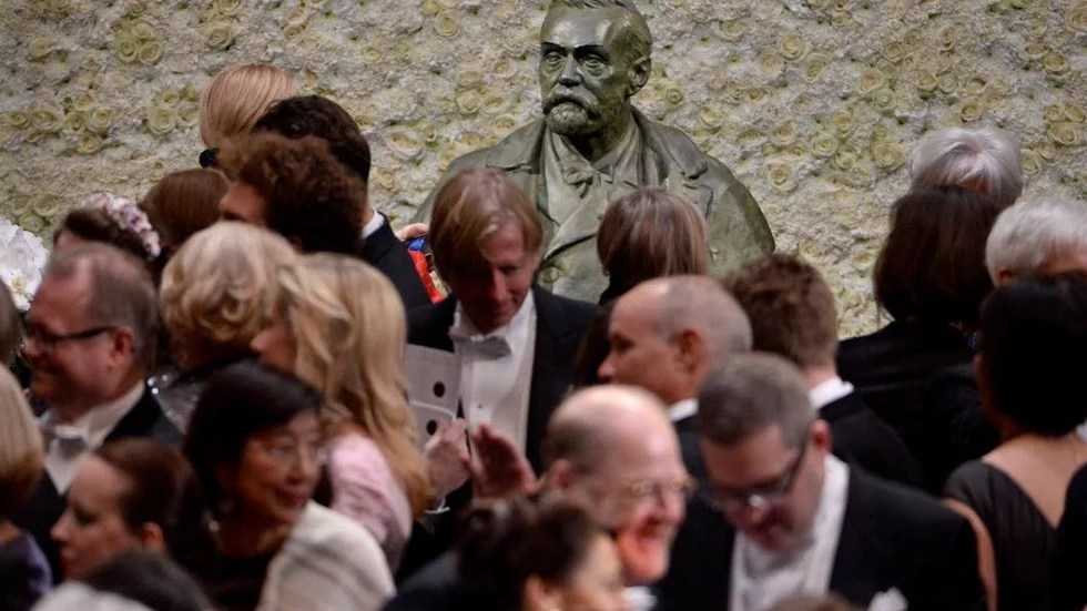 Mingel framför bysten av Alfred Nobel efter nobelprisutdelning.