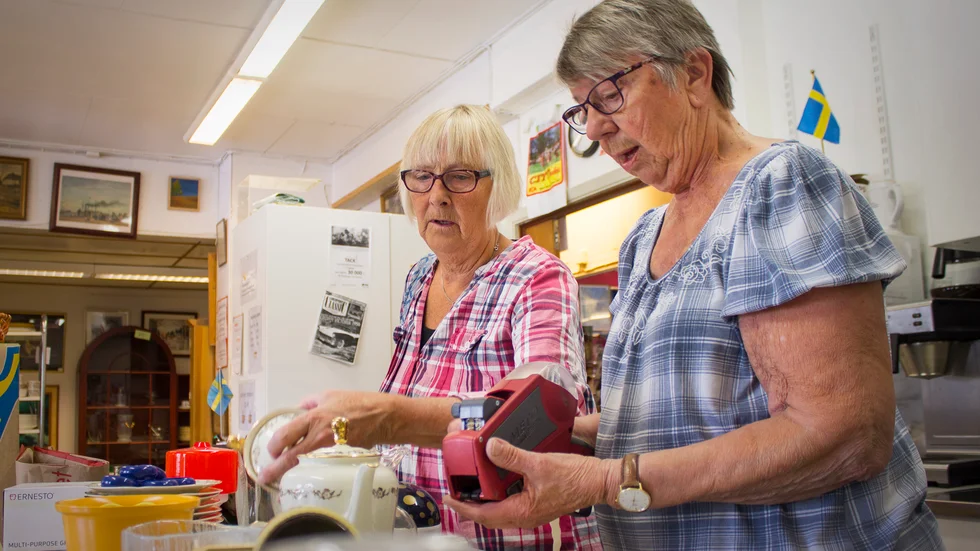 Bakom kulisserna pågår det ändlösa arbetet med att bedömma, värdera och rengöra pryttlarna som doneras till butiken. Ett trevligt arbete, om man gör det tillsammans. På bild: Catrine Lindskog och Birgitta Bergström.