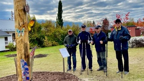 Lennart Bic, Thorsten Wikström, Raymond Engström och Kjell Vikström studerar den pelarformade träskulpturen på Holmen under promenaden.