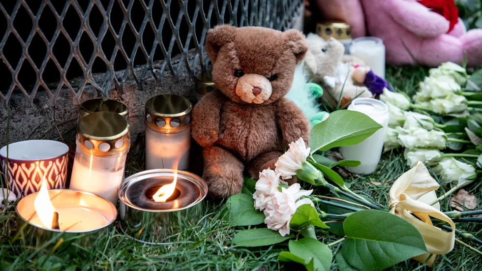 Gosedjur, blommor och ljus vid den plats där två barn hittades med livshotande skador utanför ett bostadshus i Hässelby i november. Ett av barnen avled och deras pappa åtalas nu. Arkivbild.
