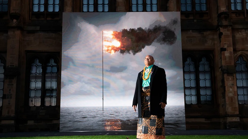 Uili Lousi, miljöaktivist, konstnär och representant för Tonga på klimatmötet i Glasgow, framför ett konstverk som visar hur Tongas flagga brinner i havet.