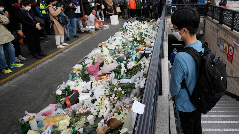 En ung man hedrar offren för lördagens halloweenfirande i Seoul, Sydkorea. Blomstermuren är nära den plats där tragedin inträffade.
