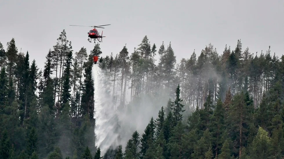 En helikopter samlar vatten i sjön Grötingen för att bekämpa skogsbranden på Grötingenberget i Bräcke kommun, Jämtland under söndagen.