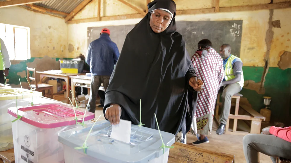 En kvinna lägger sin röst i en vallokal i Kenya.