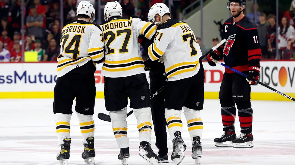 Bostons Hampus Lindholm leds av isen efter en tackling mot huvudet i matchen mot Carolina.