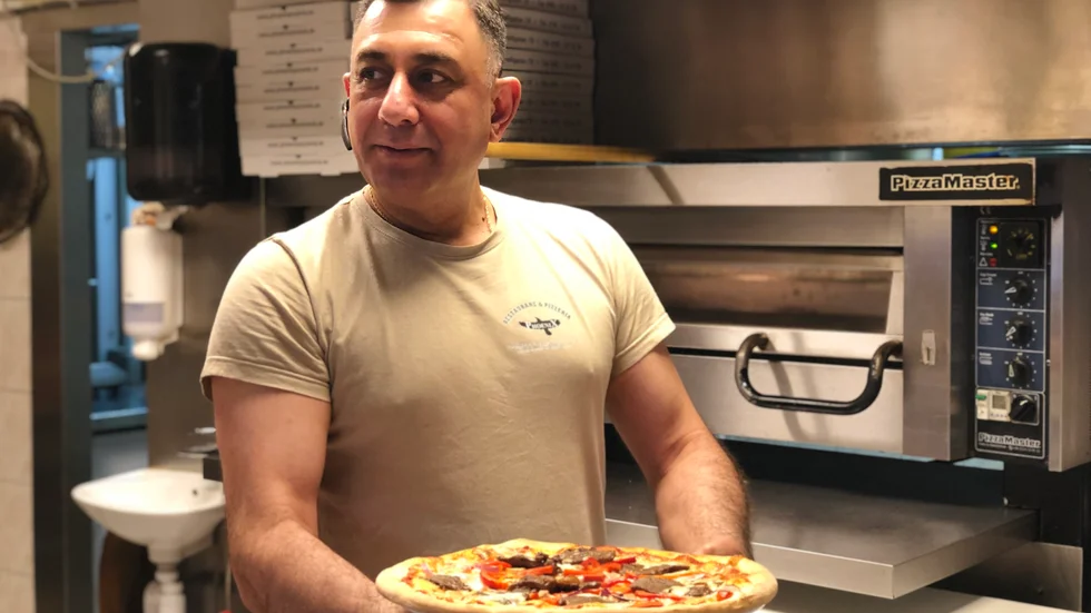 Shwan Faransi på Phoenix pizzeria håller upp en Phoenix specialpizza. Den har, liksom andra pizzor, stigit med några kronor sedan priset på ingredienserna skjutit i höjden. 