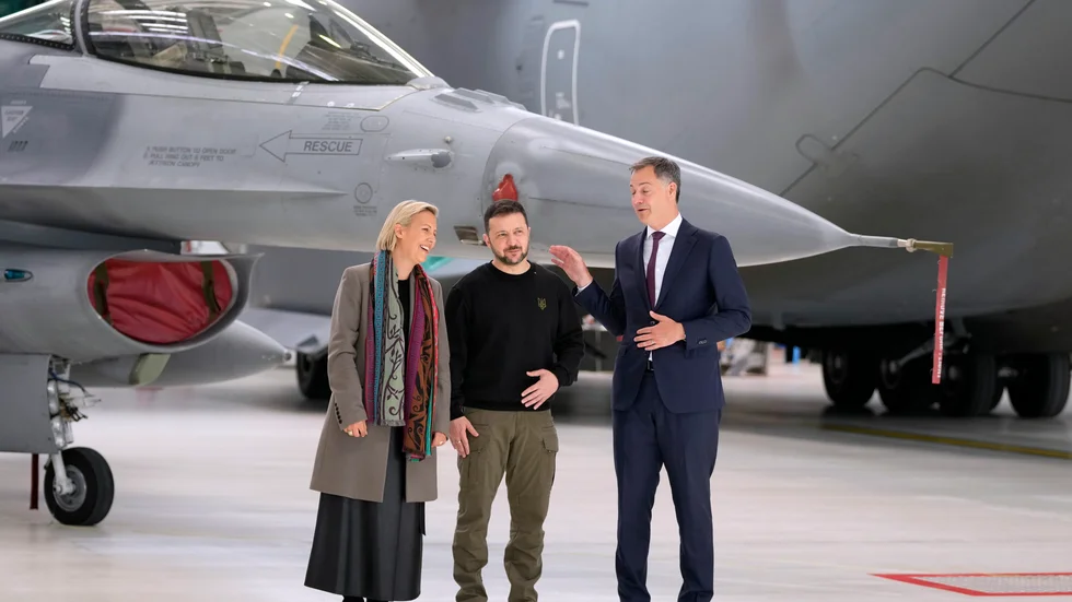 Ukrainas president Volodymyr Zelenskyj tillsammans med Belgiens premiärminister Alexander De Croo och försvarsminister Ludivine Dedonder framför F-16-plan.